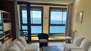 Ein Wohnzimmer mit zwei Sofas, einem Couchtisch und Meerblick durch große Fenster.