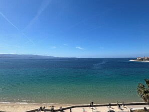 Une vue sur la côte, avec un ciel dégagé, une plage de sable et une mer calme.