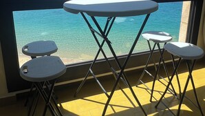 Ein Zimmer mit einem großen Fenster, einem runden Tisch und vier Hocker.