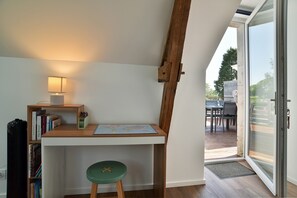Et værelse med et skrivebord, bøger, en lampe og en grøn skammel.