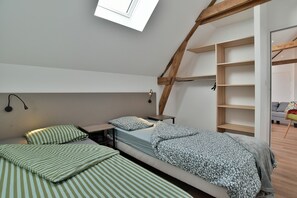 Een kamer in een studentenresidentie met stapelbedden, een dakraam en ingebouwde houten planken.