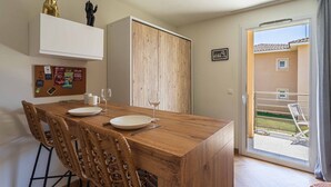 Ein Essbereich mit einem Holztisch, Korbstühlen und Blick ins Freie.