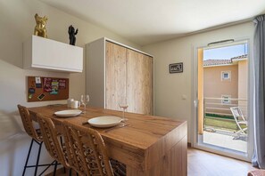Ein Essbereich mit einem Holztisch, Korbstühlen und Blick ins Freie.