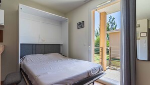 Ein Schlafzimmer mit Bett, eingebautem Kleiderschrank, einer Glastür zum Balkon und einem kleinen Nachttisch.