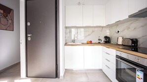 Een moderne keuken met witte kasten, een marmeren spatwand, een roestvrijstalen koelkast en een inbouwoven.