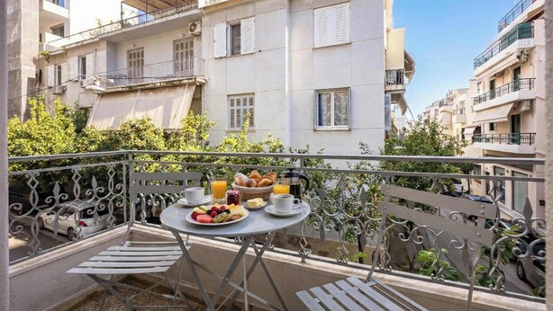 Een balkon met een tafel gedekt voor het ontbijt, inclusief fruit, gebak en een drankje.