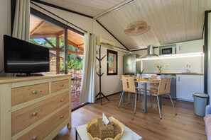 Eine moderne Küche mit Essbereich, Holzböden und einem Fernseher auf einer Kommode.