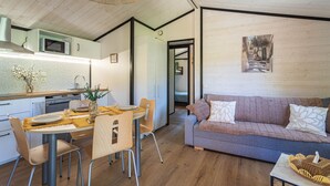 Uma cozinha moderna com micro-ondas, mesa de jantar com cadeiras e um sofá numa sala de estar.