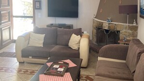 A living room with a sofa set, a television, a chandelier, and a fireplace. - Endless blue (Kitries)