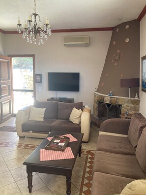 A living room with a sofa set, a television, a chandelier, and a fireplace. - Endless blue (Kitries)