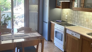 A kitchen with a dining table, chairs, a refrigerator, oven, and cabinets.