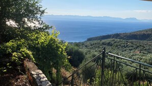 A terrace with a view of the sea, a stone wall, and a metal railing. - Endless blue (Kitries)
