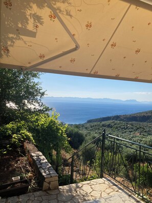 A terrace with a view of the sea, a stone wall, and a metal railing. - Endless blue (Kitries)