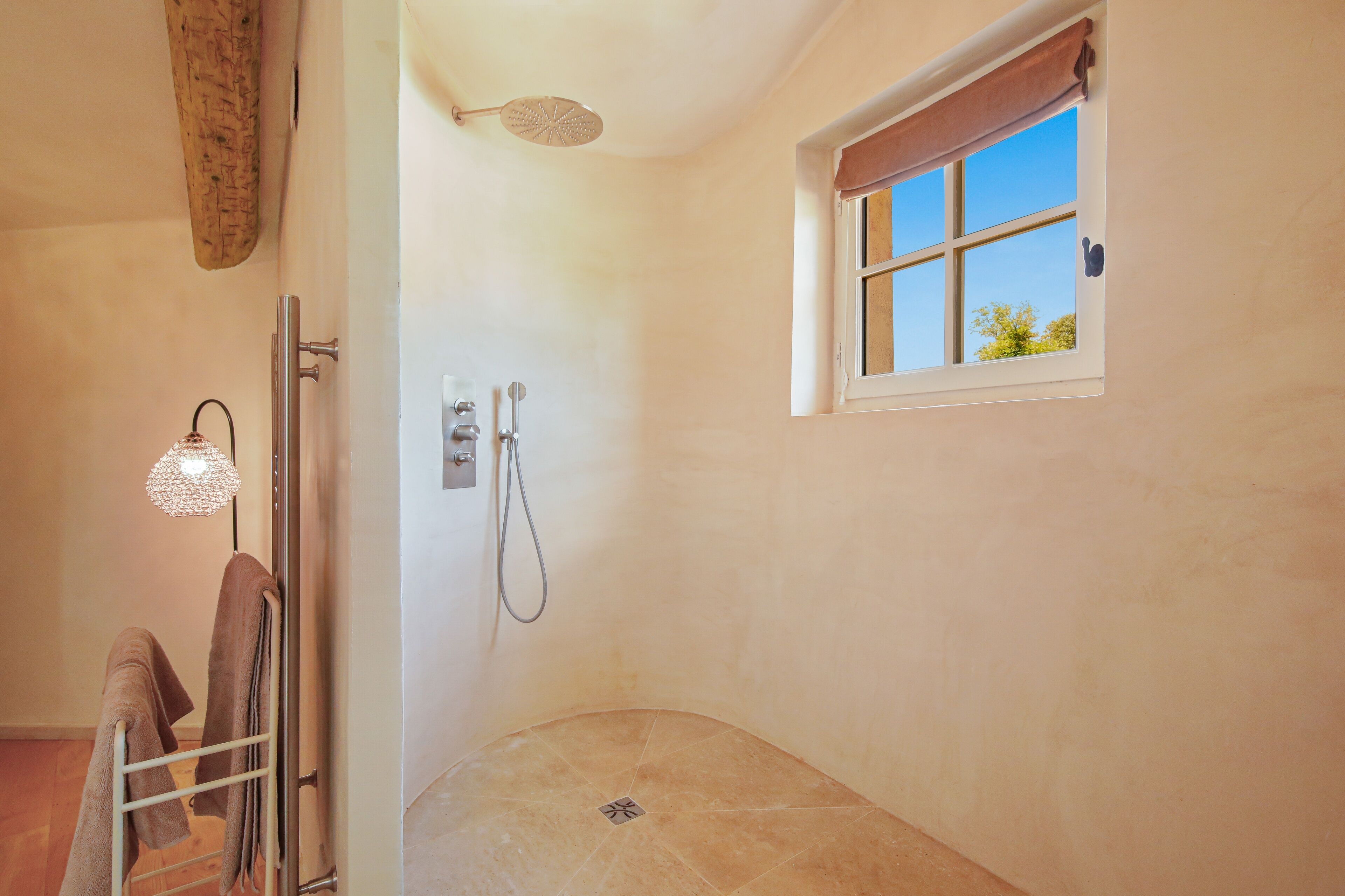 A shower with a window, a towel rack, and a light fixture.