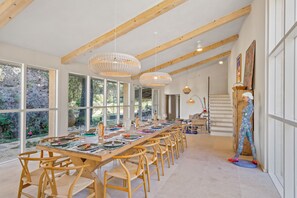 A spacious dining area with a long wooden table, multiple chairs, and large windows offering views of the outdoors. - Les 3 thyms - Avec Piscine Privée (Méounes-lès-Montrieux)