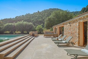 A stone building with a pool, outdoor seating, and a view of a forested hill. - Les 3 thyms - Avec Piscine Privée - (Méounes-lès-Montrieux)