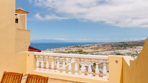 A balcony with a view of a coastal town, a table with chairs, and a red roof. - Bright 1-Bedroom Apartment with Private Terrace and Views | Pool (Playa de las Américas)