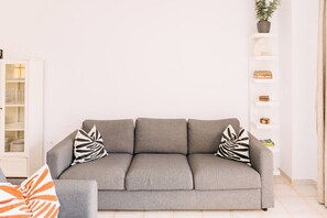 A grey sofa with zebra-patterned pillows, a white cabinet with glass doors, and a shelf with decorative items. - Bright 1-Bedroom Apartment with Private Terrace and Views | Pool (Playa de las Américas)