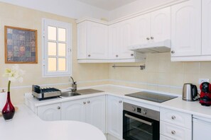 A modern kitchen with white cabinets, a stainless steel sink, a built-in oven, and a window with a view. - Bright 1-Bedroom Apartment with Private Terrace and Views | Pool (Playa de las Américas)