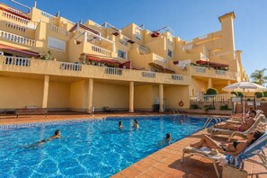 A swimming pool with people in it, surrounded by a building with balconies. - Bright 1-Bedroom Apartment with Private Terrace and Views | Pool (Playa de las Américas)