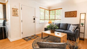 A living room with a sofa, a coffee table, a door, and a window with blinds. - Stay In The Quiet Side of Denver by Sloan’s Lake (Denver)