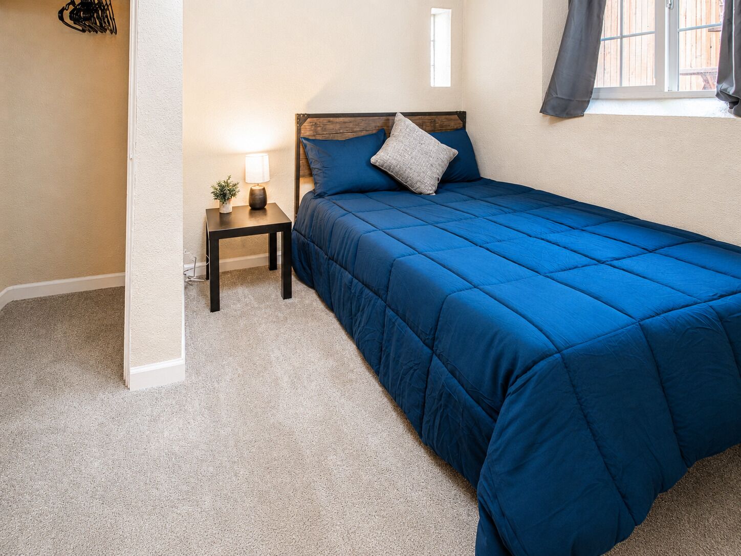 Ein Schlafzimmer mit einem großen Bett, einem Nachttisch mit Lampe und einer kleinen Pflanze.