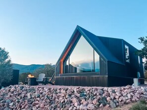 Ein modernes Haus mit großem Panoramafenster, Steinbruchfundament und Feuerstelle.