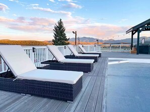 Eine Terrasse mit Liegestühlen und einer Pergola mit Blick auf eine gebirgige Landschaft.