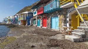 A coastal building with colorful doors and balconies, a stone staircase, and a view of the sea.
