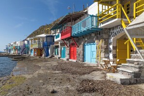 A coastal building with colorful doors and balconies, a stone staircase, and a view of the sea. - Ky-ma Boat House (Milos)