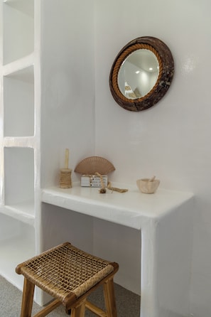 A white console table with a round mirror, a candle holder, a small box, a fan, and a mortar and pestle.