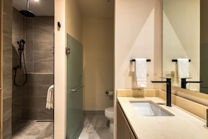 Een moderne badkamer met een douche, toilet en wastafel.