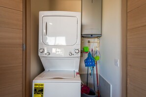 A compact laundry room with a front-loading washer and dryer, a water heater, and a mop and bucket. - Bright Coastal Condo With Ocean-view Balcony, Gym, Pools, BBQ & Kids Park (Cabo San Lucas)