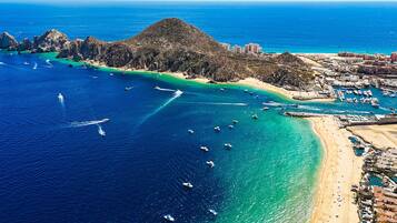An aerial view of a coastal area with a beach, boats, and buildings.