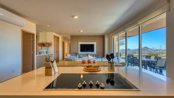 A modern kitchen with an island, a flat-screen TV, and a dining area with a view.
