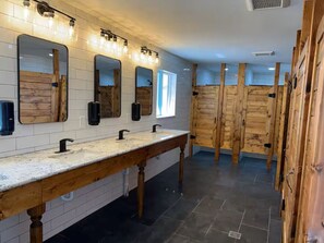 Des toilettes publiques dotées d’un long meuble-lavabo, de plusieurs miroirs et de panneaux de bois.