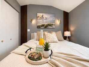 Una cama bien hecha con una bandeja de desayuno, un cuadro en la pared y una lámpara de noche.