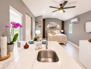 A modern bedroom with a large bed, bedside lamps, a ceiling fan, and a view of the outdoors. - Cozy Escape Free Parking Private Patio (Miramar)