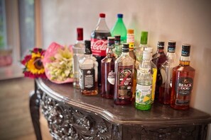 Une sélection de bouteilles de spiritueux disposées sur une table sombre, richement sculptée.
