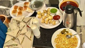 Une table sur laquelle on trouve divers aliments, notamment des sandwichs, des en-cas frits et une assiette de sev.
