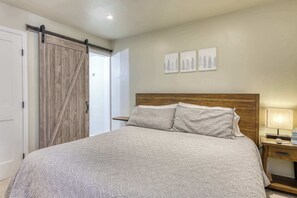 Ein Schlafzimmer mit einem Bett, einem hölzernen Kopfteil, einem Nachttisch, einer Lampe und einer Schiebetür.