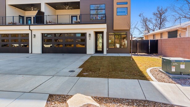 Een modern huis met twee verdiepingen, een overdekt balkon, een garage met twee auto’s en een verzorgd gazon.