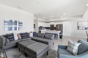 Ein modernes Wohnzimmer mit einem grauen Ecksofa, einem grauen Sessel und einem Couchtisch.