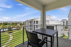 Ein Balkon mit Tisch und Stuhl, mit Blick auf einen Pool und Grünflächen.