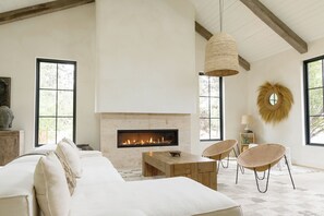 A modern living room with a fireplace, large windows, and a cozy seating area.