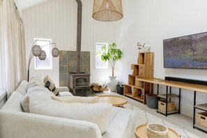 A living room with a sofa, a fireplace, a television, and a large window.