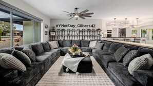 A modern living room with a sectional sofa, a coffee table, and a ceiling fan. - YNotStay_GilbertAZ - Spacious Gilbert Getaway Private Pool Home Retreat (Gilbert)