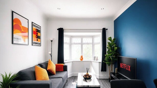 Ein modernes Wohnzimmer mit einer Couch, einem Couchtisch und einem Fernseher, der 'NETFLIX' anzeigt.