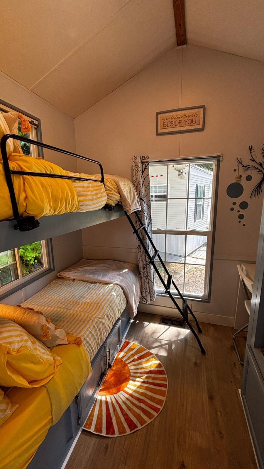 Quarto com beliche, janela e tapete pequeno.