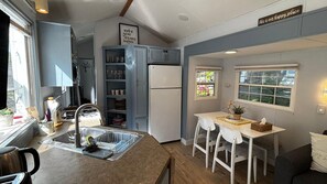 Une cuisine compacte comprenant un évier, un réfrigérateur et un coin repas avec une table et des chaises.